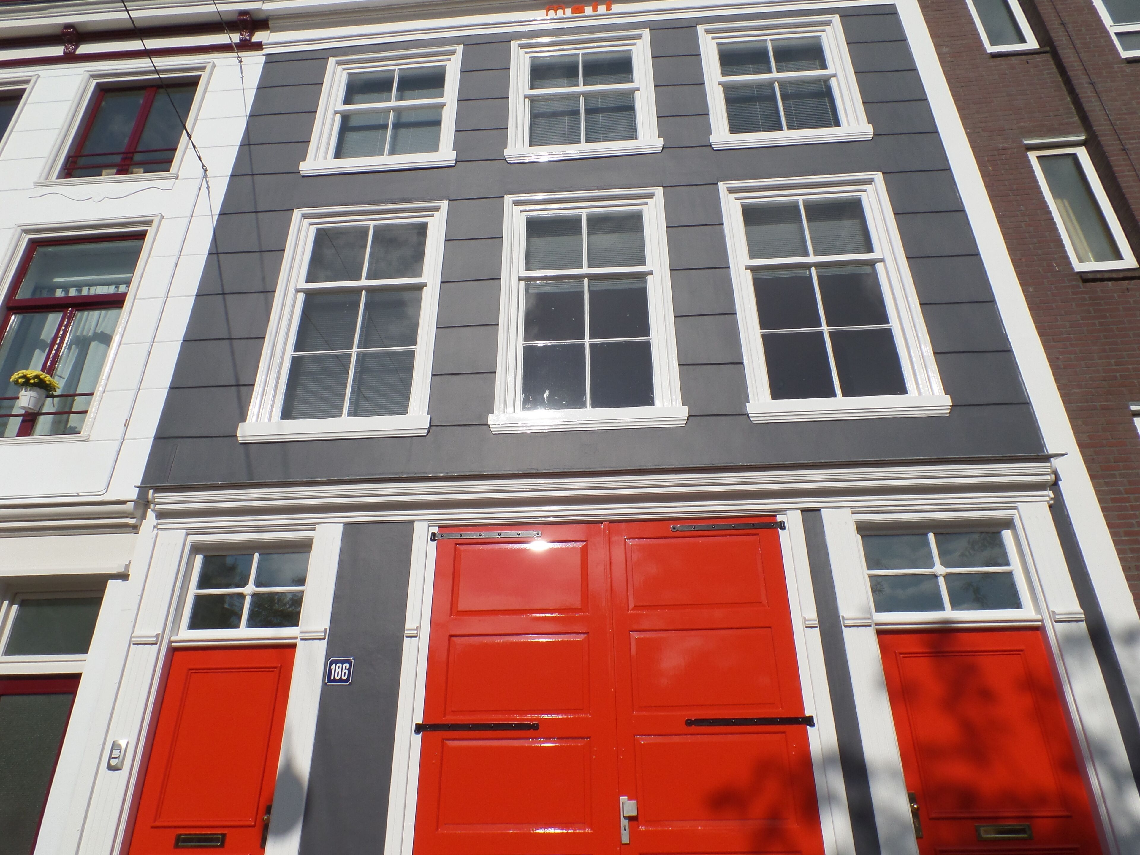 A multi-story building with a red door and white-framed windows.