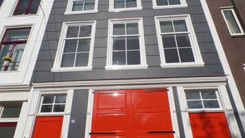 A multi-story building with a red door and white-framed windows.