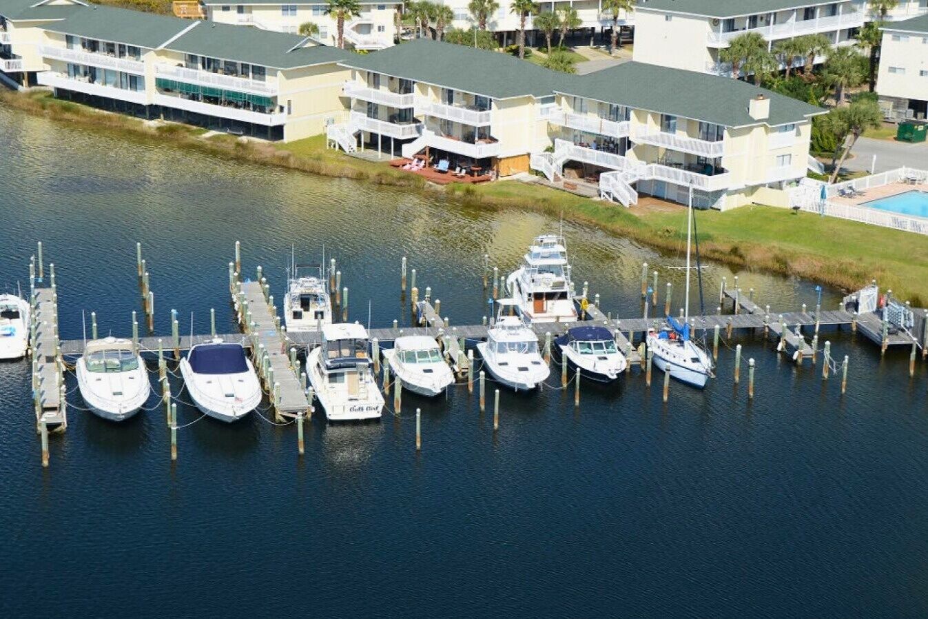 A marina with several boats docked, connected to a building with multiple balconies.