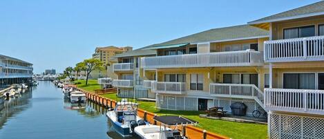 A marina with boats docked alongside a row of multi-story buildings with balconies.