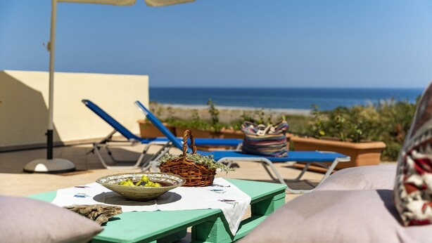 A terrace with a table set for a meal, overlooking a beach. - Live by the sea at House Almyra (Rhodes)