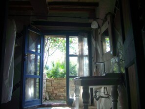 Une salle de bain rustique avec une grande fenêtre, un lavabo et un plafond en bois.