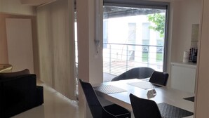 A modern dining area with a table and chairs, a window with a view of the outside, and a door leading to another room.