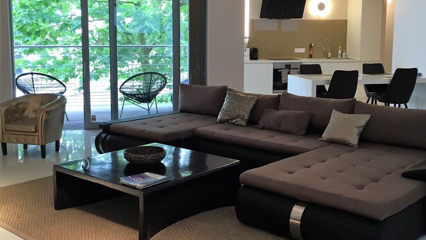 A modern living room with a sectional sofa, a coffee table, and a dining area with chairs.