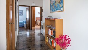 A hallway with a wooden bookshelf, a map on the wall, and a washing machine in the background. - Large apt 2 bedrooms &free car park (Venezia)
