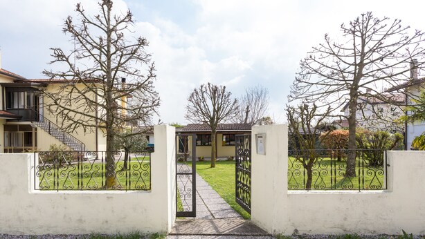 A gated entrance with a pathway leading to a building with a tiled roof and a visible staircase. - Large apt 2 bedrooms &free car park (Venezia)