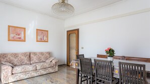 A living room with a sofa, dining table, chairs, and a chandelier. - Large apt 2 bedrooms &free car park (Venezia)