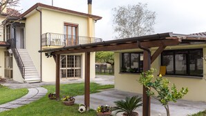 A two-story house with a balcony, a covered patio, and a small garden with potted plants. - Large apt 2 bedrooms &free car park (Venezia)