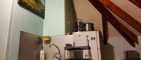A compact kitchen with a sink, a small refrigerator, and a stove.