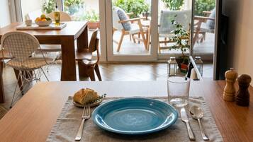 A dining table with a blue plate, cutlery, and a loaf of bread.