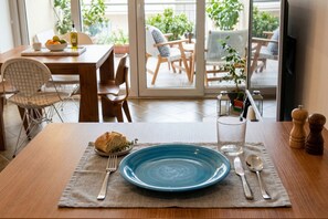A dining table with a blue plate, cutlery, and a loaf of bread.