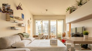 A modern hotel room with a bed, a desk, a TV, and a balcony with a city view. - Appartamento Gassman - Holiday Apartment in Milano (Milano)