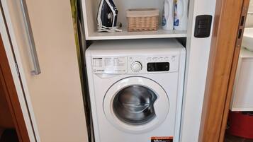 A compact, white front-loading washing machine with a control panel and a label indicating a capacity of 10 kg.
