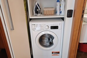 Lavadora blanca de carga frontal, compacta, con panel de control e indicador de capacidad de 10 kg.