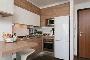 Une cuisine moderne avec des meubles en bois, un réfrigérateur blanc, un four et un four à micro-ondes.