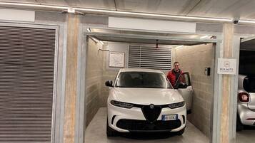 A white car parked in a garage with a sign reading 'BOX AUTO'.