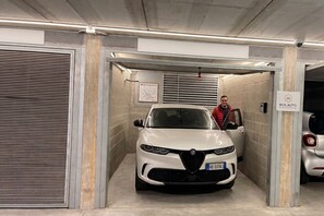 A white car parked in a garage with a sign reading 'BOX AUTO'.