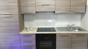 Une cuisine moderne avec des meubles en bois clair, un évier en acier inoxydable et un lave-vaisselle noir.