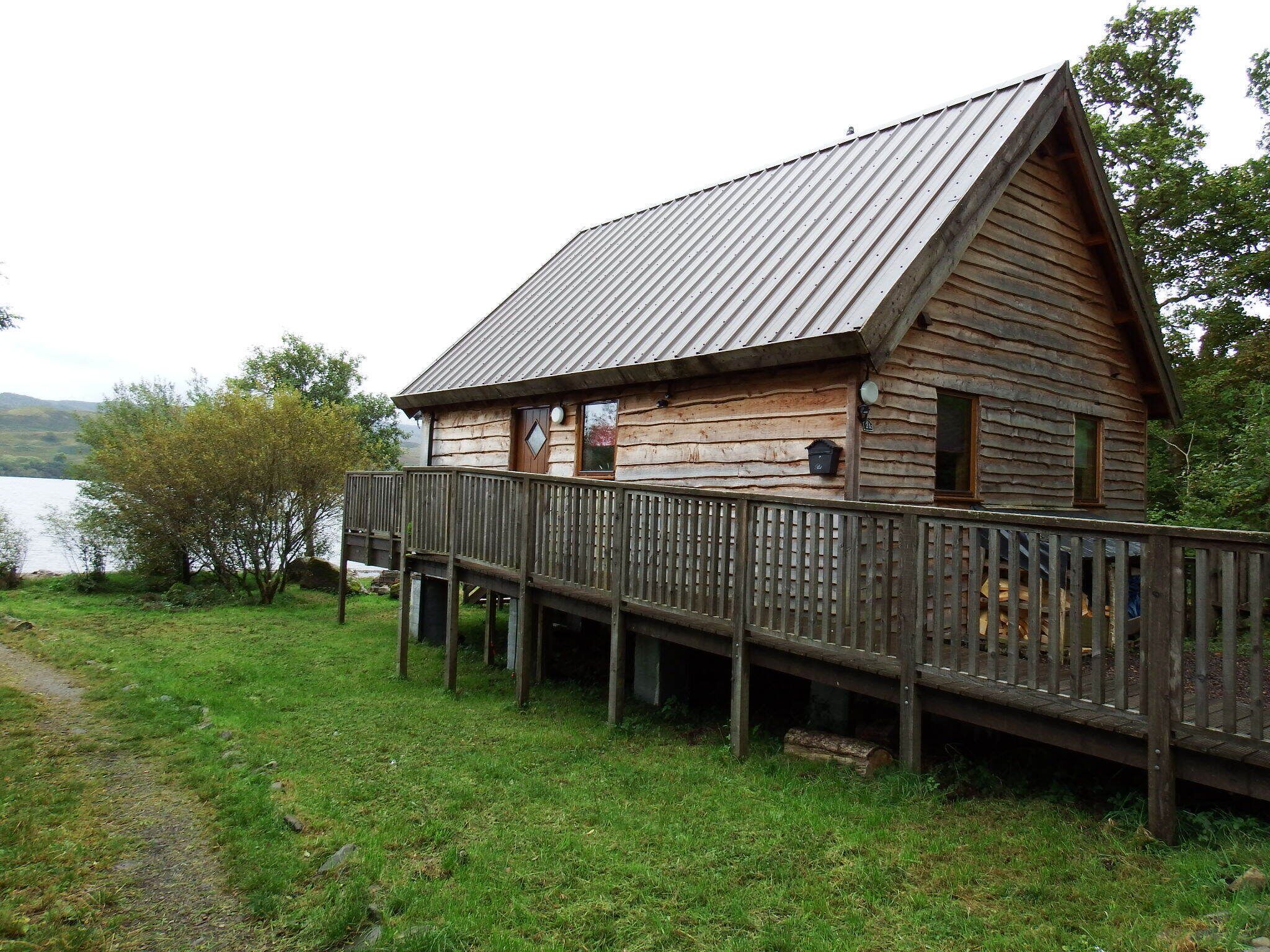 Een houten hut met terras, gelegen aan een meer.