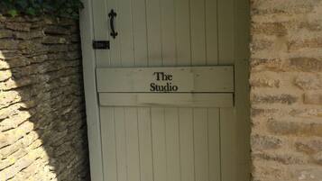 A white wooden gate with the words "The Studio" on it, leading to a stone wall.