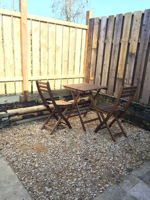 Enjoy a meal or relax with friends on the patio, surrounded by a fence and featuring a table and chairs.