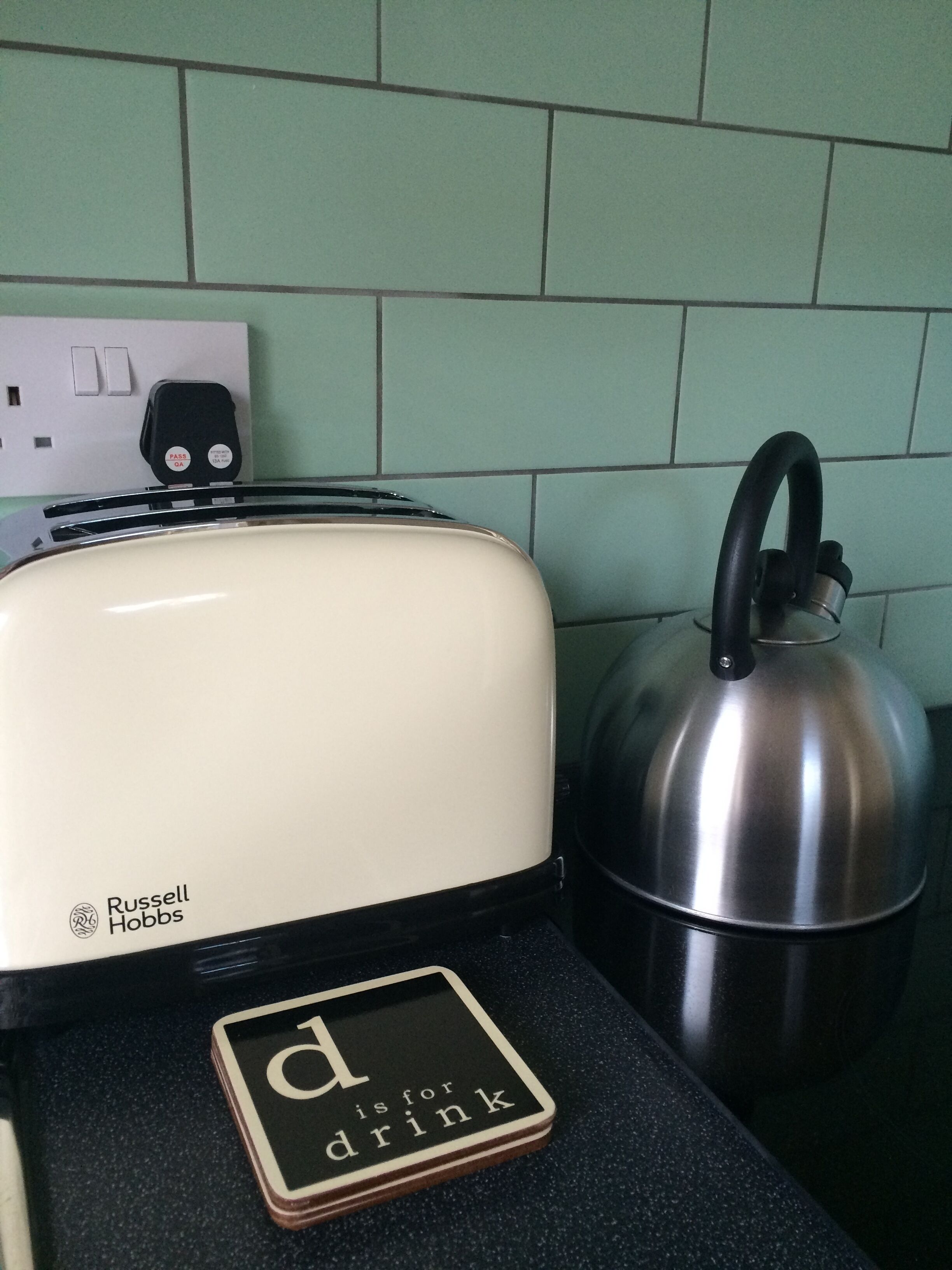 Eine Küche mit einem weißen Toaster, einem Wasserkocher und einer schwarzen Arbeitsplatte.