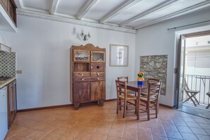 Een eetgedeelte met een houten tafel en stoelen, een kast met glazen deuren en een stenen muur.