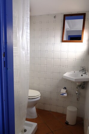 A bathroom with a toilet, sink, and trash can. - Casa Bordonaro B (Cefalù)