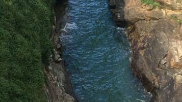 Un cañón estrecho con un río que lo atraviesa, rodeado de acantilados rocosos y abundante vegetación.