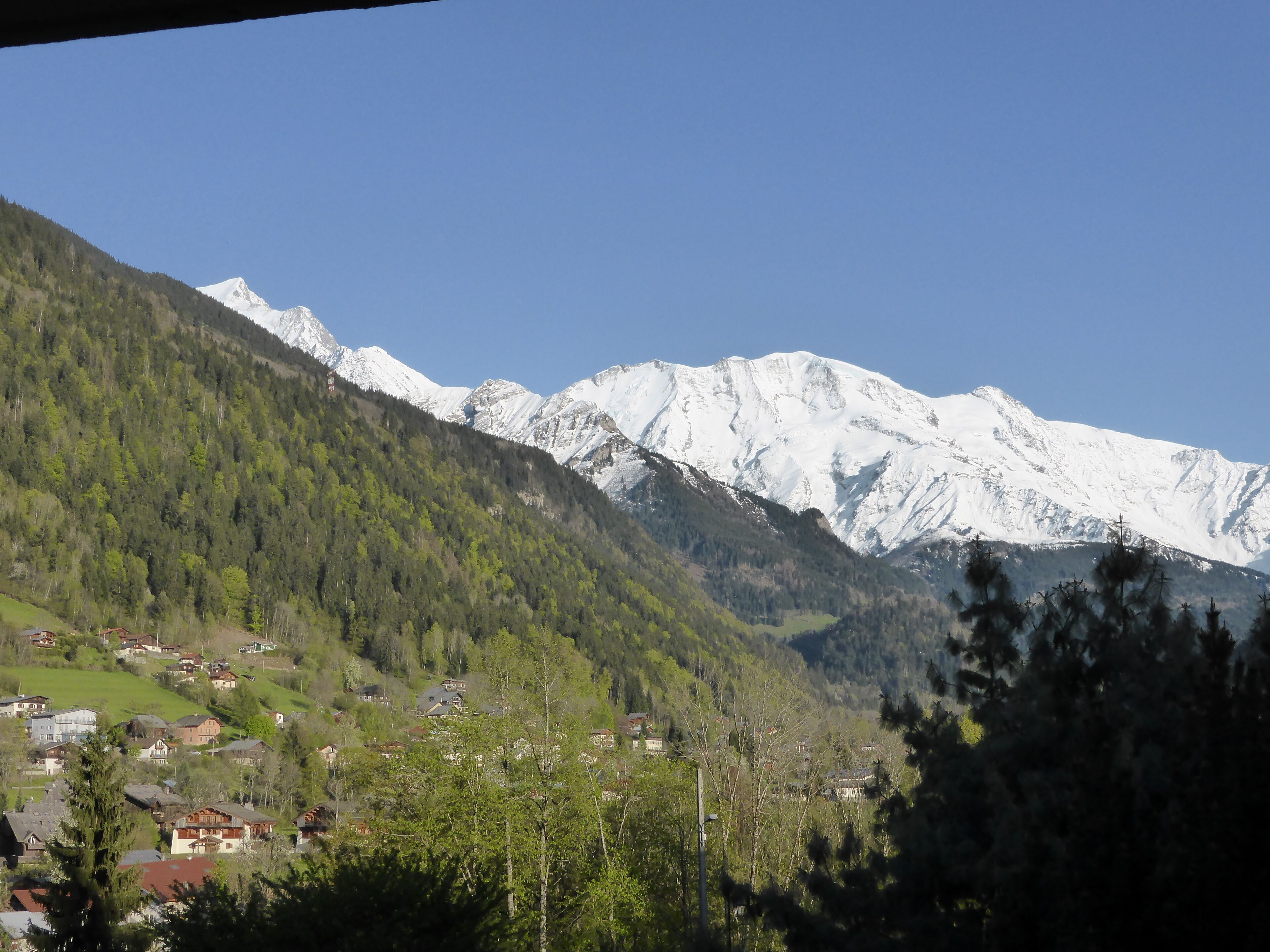 A mountainous landscape with snow-capped peaks and a small village with houses.