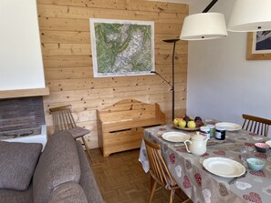 A cozy dining area with a wooden table set for two, a bench, and a map on the wall.