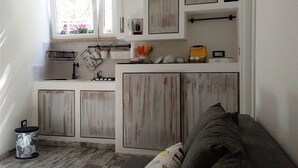 A compact kitchen with white cabinets, a window, and a small countertop.