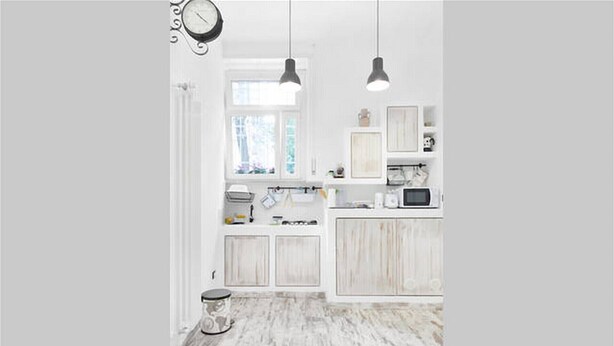 A kitchen with white cabinets, a microwave, and hanging pendant lights.