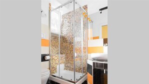 A modern bathroom with a glass shower enclosure, a toilet, and a sink with a mirror.