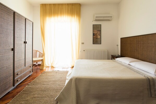 Een slaapkamer met een groot bed, een kledingkast, een stoel en een radiator.
