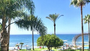 A beachside resort with palm trees, lounge chairs, and a sign indicating pool rules. - Mi CAPRICHO 9A BEACHFRONT:Apartment with sea view (Mijas)