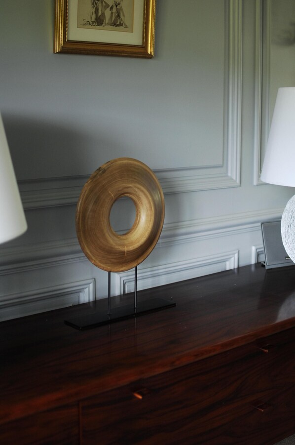 A wooden object on a stand in a room with a framed picture on the wall and a lamp on the side. - Cotswolds Thatch Cottage, countryside views, walk to shops. (Broadway)