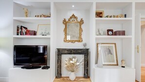 A living room with a fireplace, a television, and shelves with books and decorative items. - Downtown Rome, Vatican - St. Peter's area.  Elegant 3-bedroom, 2-bathroom apartment (Roma)
