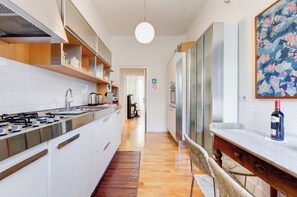 A modern kitchen with white cabinets, stainless steel appliances, and a wooden floor.