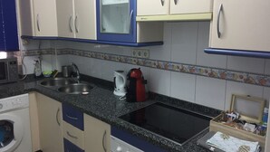 Cuina amb rentadora, microones, rentapelats, fogó i armaris.