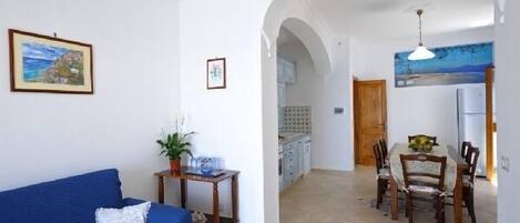 Sala de estar com um sofá azul, uma mesinha com uma planta e um quadro na parede.
