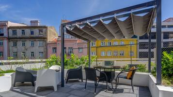 Eine Terrass mit moderner Möbel, einer Pergola und Blick auf farbenfrohe Häuser.