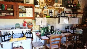Una tienda de vinos con estantes llenos de botellas, un mostrador con caja registradora y diversos artículos relacionados con el vino.