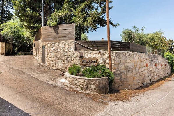 A stone wall with a wooden structure and a sign that reads "Alla Aton." - Traditional  Stone Villa With Pool And Nice View. (Maza)