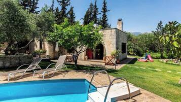 Relax by the serene pool surrounded by lush greenery and a children's play area.