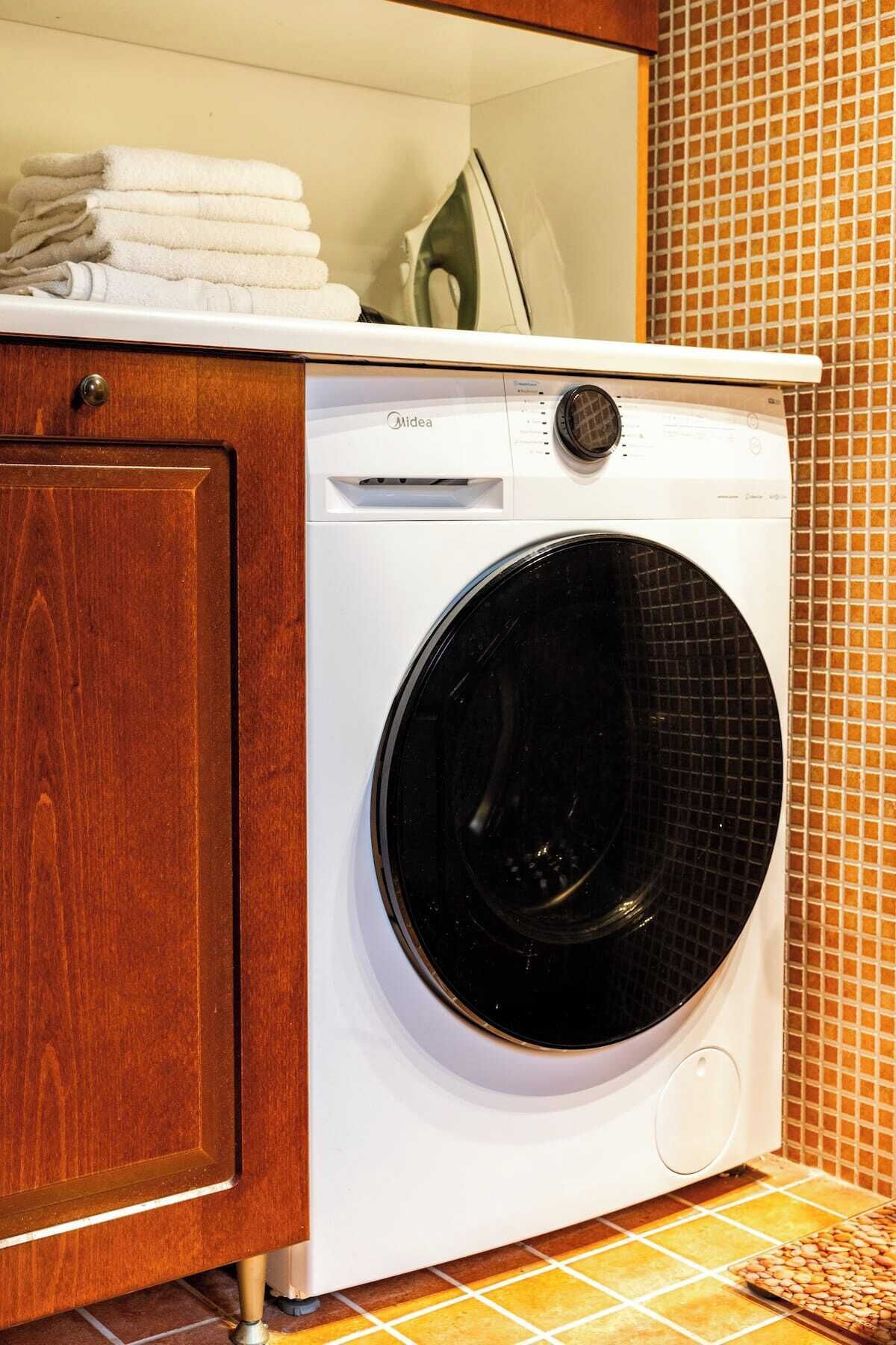 Une machine à laver compacte, de couleur blanche, à chargement frontal, avec un panneau de commande situé sur le dessus.