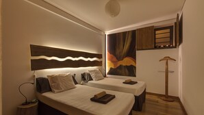 A hotel room with two beds, a nightstand, a lamp, a painting, and a wooden floor. - Apartment with Garden and Jacuzzi. Sea view. Fully equipped. (Lagoa - Açores)