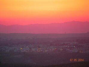 A sunset over a cityscape with distant mountains.