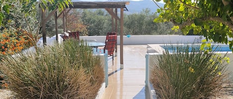 Un patio cubierto con piscina, rodeado de follaje y vistas a las montañas.