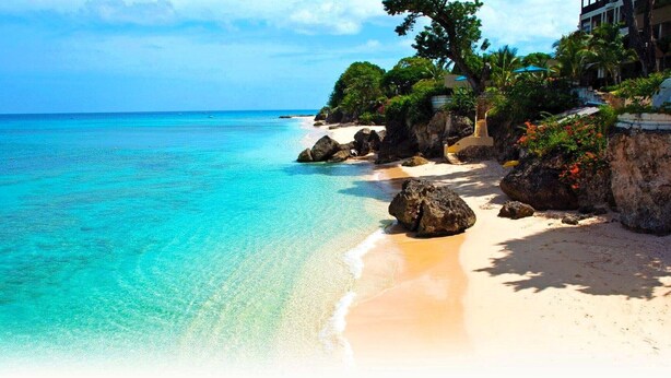 A beach with clear turquoise water, sandy shore, and lush greenery. - 2 Bed Apartment close to Dover Beach (Oistins)